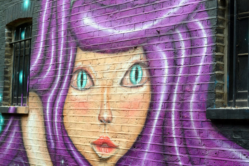 Camden street art tour. Girl with purple hair. Just one of the many pieces of Camden street art you can encounter when taking the time to explore the Camden area.