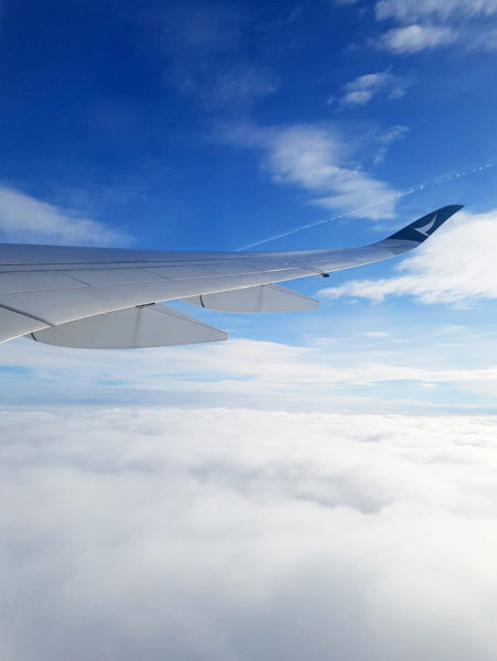 The view from a plane window. Plane wings, clouds, and blue sky. Just one of many things to expect on a long haul flight. 