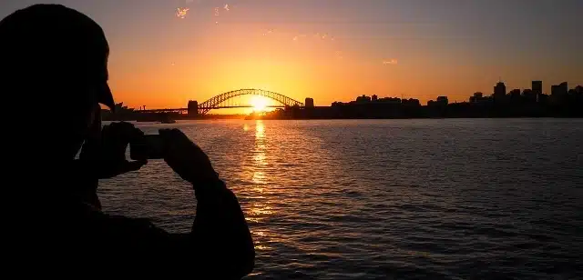 Russ taking a photo of the setting sun behind the Sydney Harbour Bridge