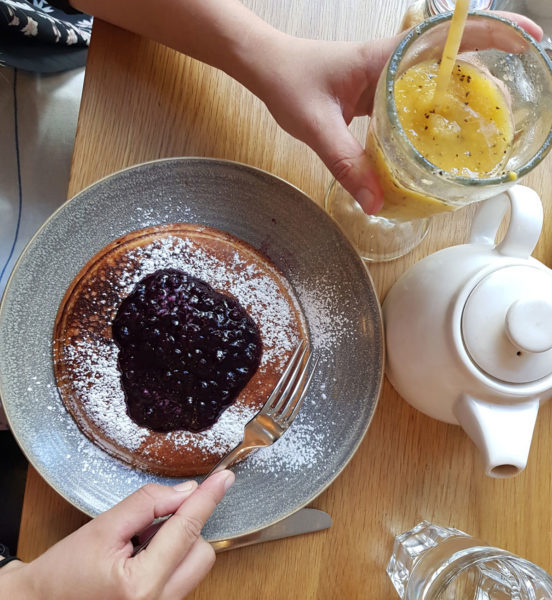 Brunch pancakes on table with a glass of juice. Just one of the many things to eat during your weekend getaway in Chester.