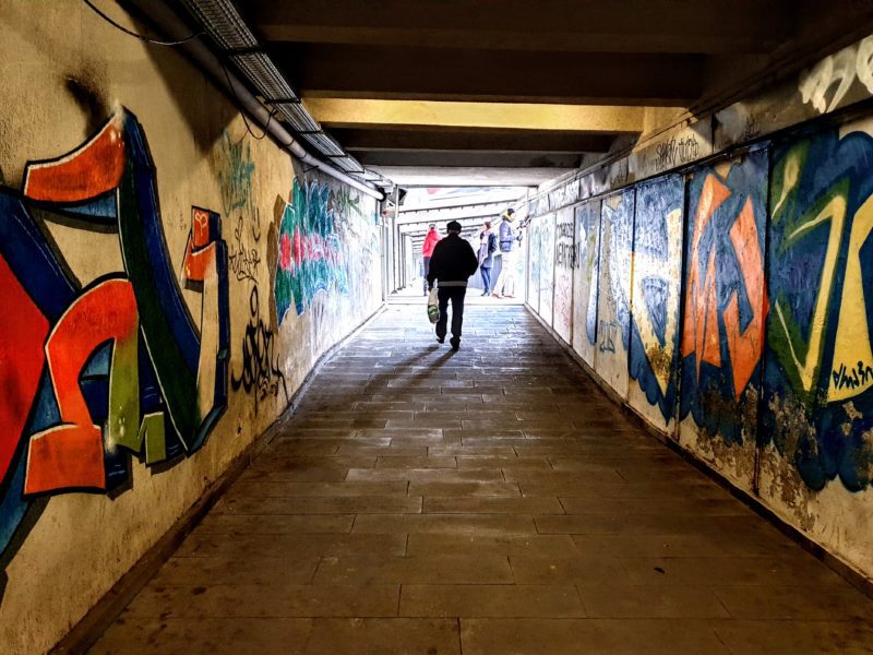 man walking through street art tunnel