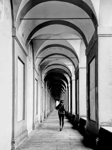 Black and white photo of jogger running through the San Luca Bologna porticoes