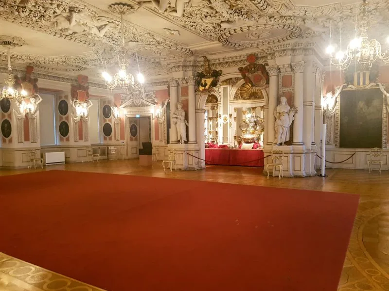 Large state room with red carpet and multiple chandeliers hanging from the ceiling. Friedenstein Castle, Gotha