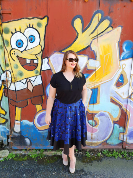 Roma standing in front of graffiti wall wearing blue midi skirt. Midi skirts are perfect for travel.