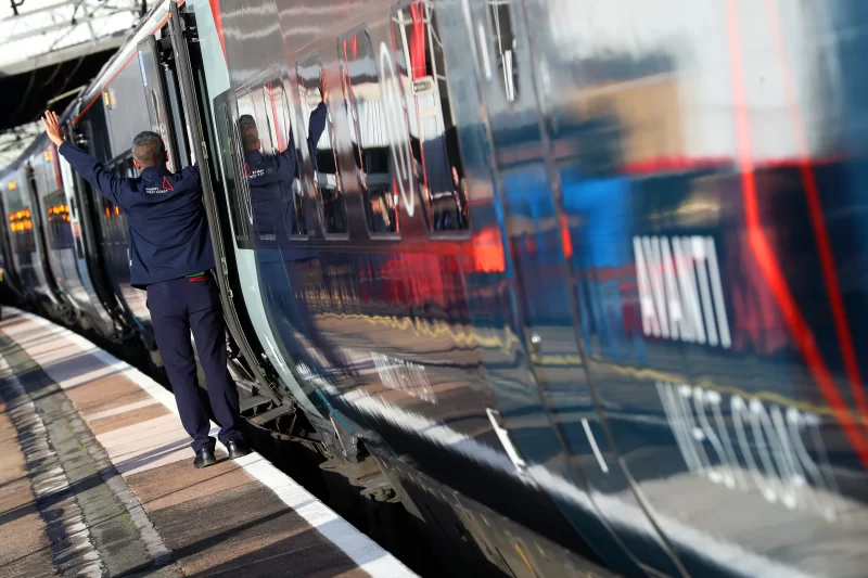 Avanti crew member standing on platform close to train carriage. Just one of many ways to help you maximise saving for a holiday.