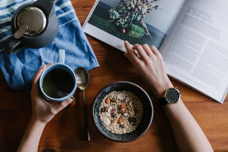 Breakfast table with person reading magazine whilst having a coffee and cereal