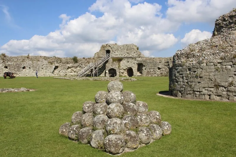The interior of Pevensey Castle, a pile of cannon balls piled up into a pyramid