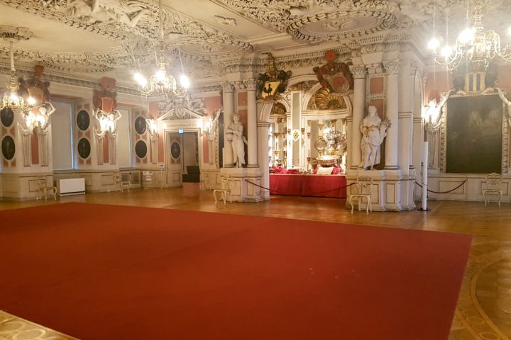 Large state room with red carpet and multiple chandeliers hanging from the ceiling. Friedenstein Castle, Gotha www.roamingrequired.com