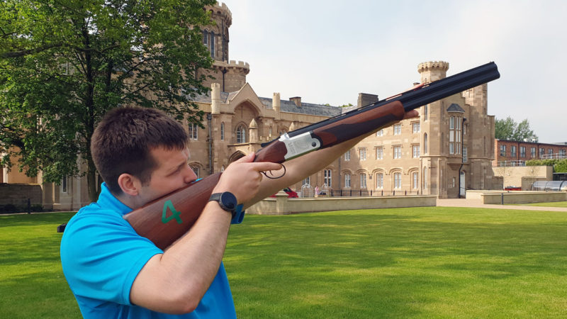Man in blue shirt holding laser clay rifle at Studley Castle