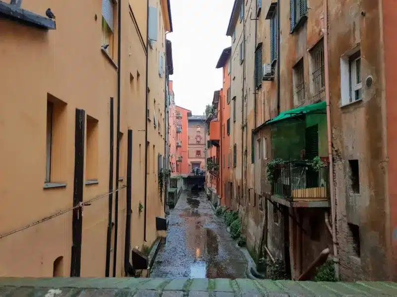 A small trickle of water between buildings which are the remains of Bologna's canals