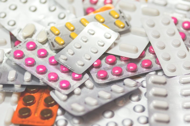 A flat lay of pill packets, some pills are yellow, others white or yellow. 