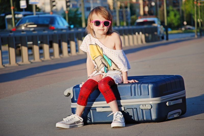 Young girl sitting on a suitcase