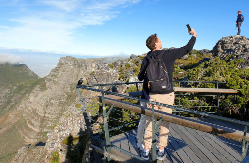 Man taking a selfie from Table Mountain with Cape Town in the background