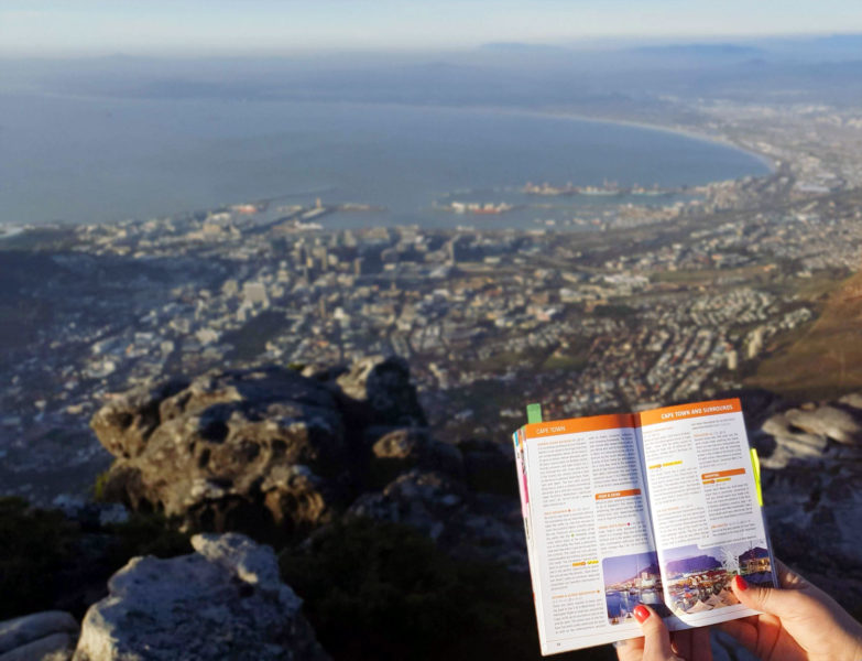 Roma reading a guide book from Table Mountain in Cape Town 