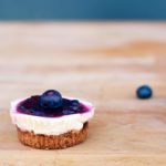 Homemade mini cheesecake with blueberry coulis on top on a wooden board