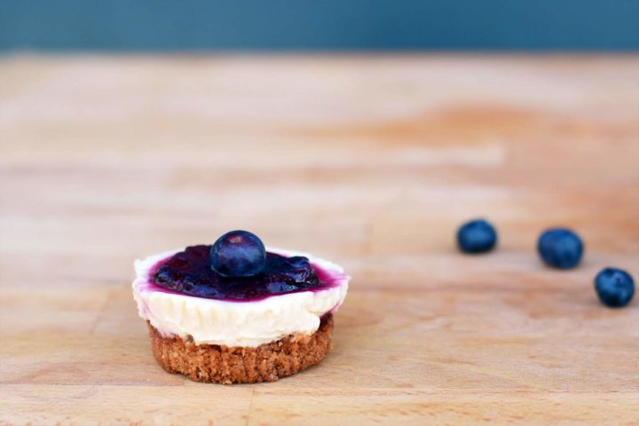 Homemade mini cheesecake with blueberry coulis on top on a wooden board