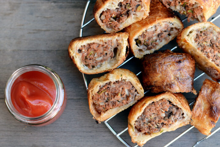 Australian sausage roll on a metal plate with a jar of ketchup (tomato sauce)