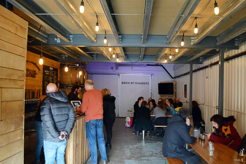 Interior of BBNO bar with people at tables drinking beer