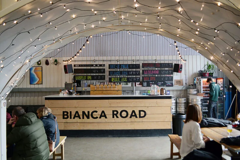Interior of Bianca Road brewery with bar and taps visible and people drinking beers at tables