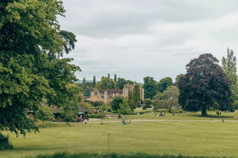 Exterior of Hever Castle surrounded by green grass and leafy green trees. Just one of many places to include on this list of car day trips from London