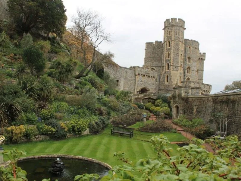 Exterior of Windsor Castle with green grass in foreground. Just one of many places to include on this list of car day trips from London