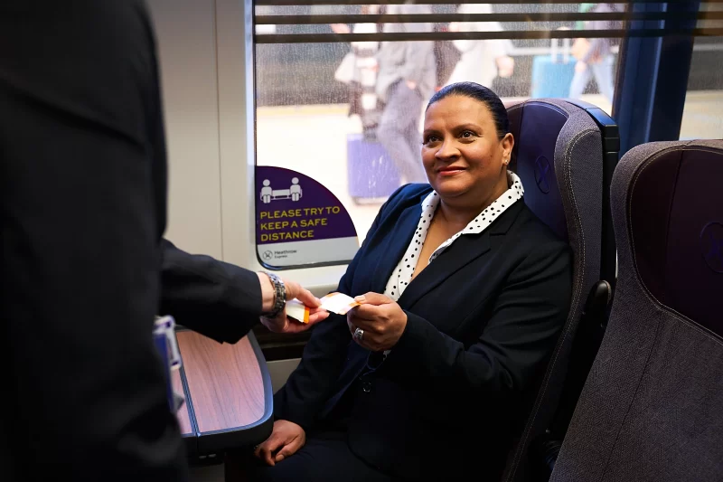 Business class passenger handing ticket to Heathrow Express staff member