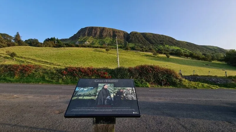 A roadside sign with scenes from Game of Thrones with green rolling hills in the background