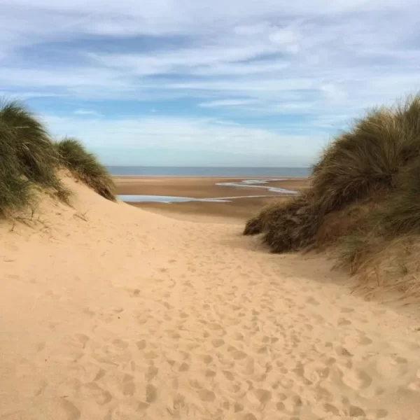 Sand-filled photo with water in the background. One more fantastic place to visit to add to your day trips from London list
