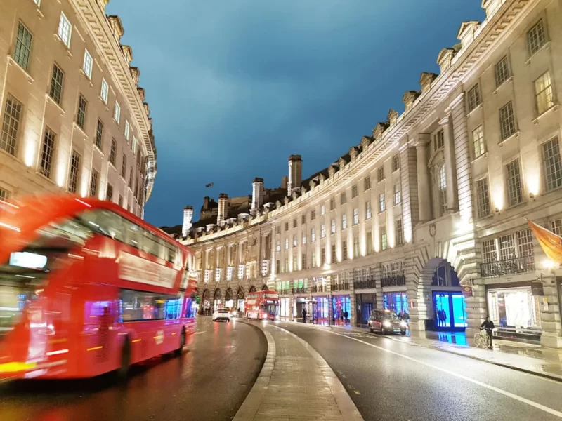 An evening photo showing the crescent shape of Regent Street with light trails showing a passing London bus 