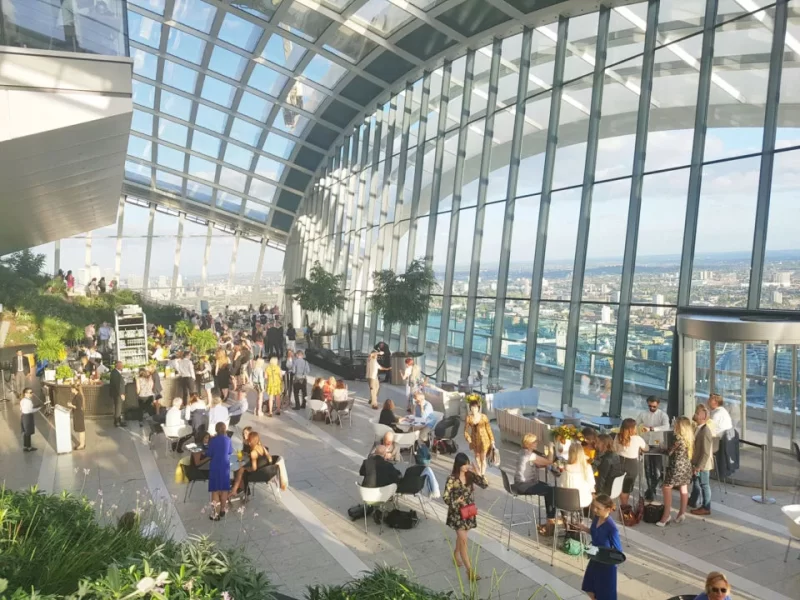 Interior view of the Sky Garden in The Shard which shows groups of people enjoying the view through the large windows