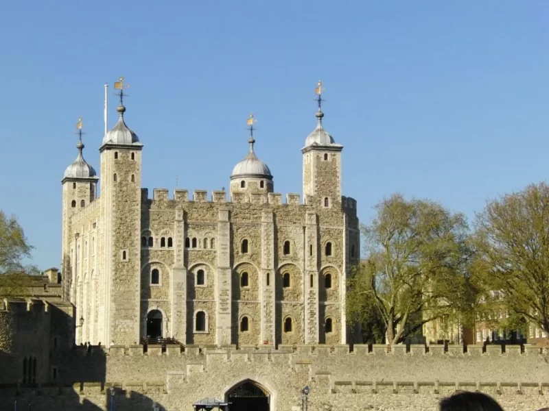 A view of the Tower of London set against a clear blue sky captured from the river. 