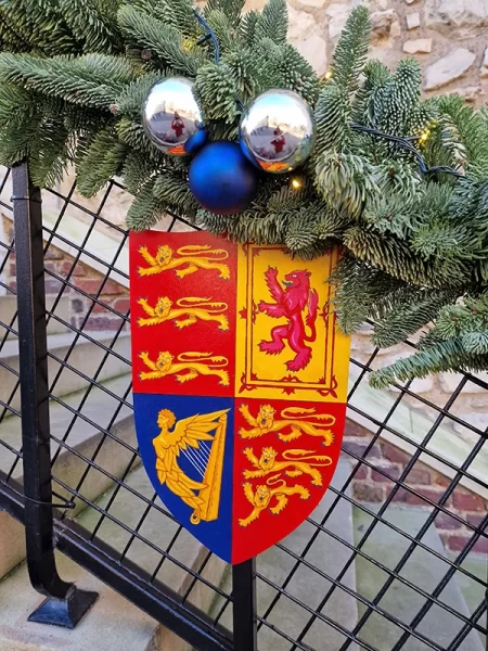 Coat of arms shield under Christmas decorations near Tower of London stairs