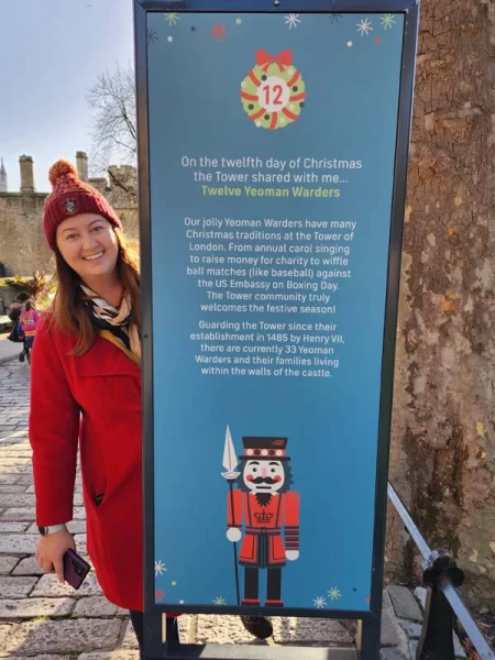 Roma peeking out from behind a sign at the Tower of London smiling