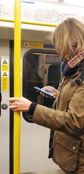 Female holding onto vertical handrail on the Circle Line on the London Underground