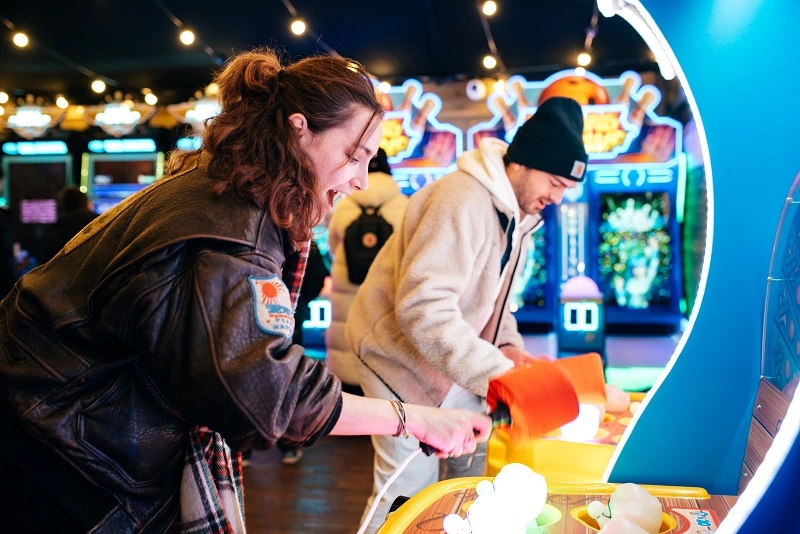Couple playing whack-a-mole game at Winter Wonderland in London