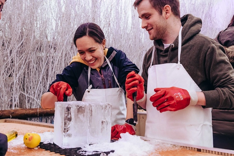 A couple at an ice sculpting workbench working on a block of ice