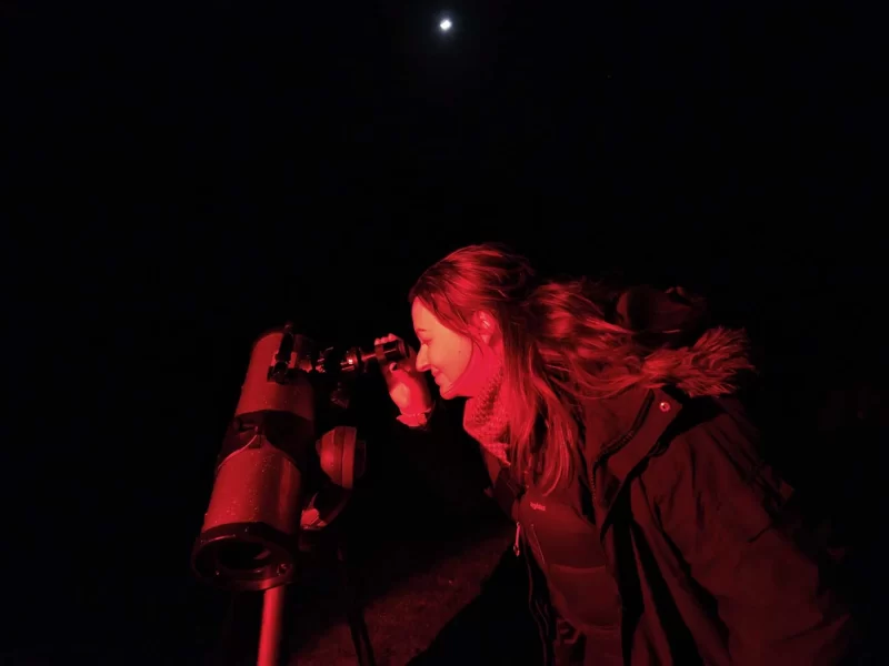 Roma looking through a telescope at the pristine night sky at a dedicated dark sky reserve. Just one of the many things to do in the North York Moors. 