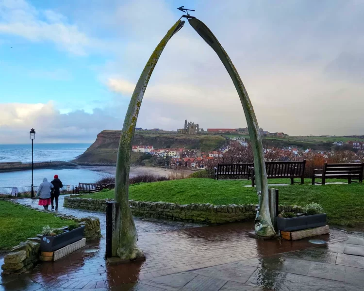 The Whalebone Arch with Whitby Abbey and harbour in the background