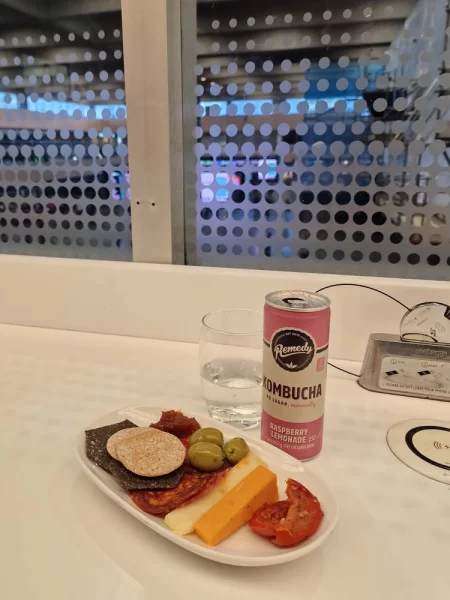 Plate of snacks and a can of Kombucha at the Avanti West Coast First Class Lounge