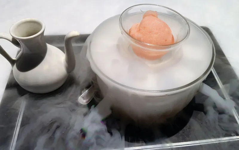 A glass dish with pink grapefruit sorbet and dry ice at Le Petit Chef