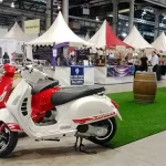 A series of vespas in front of stallholder tents