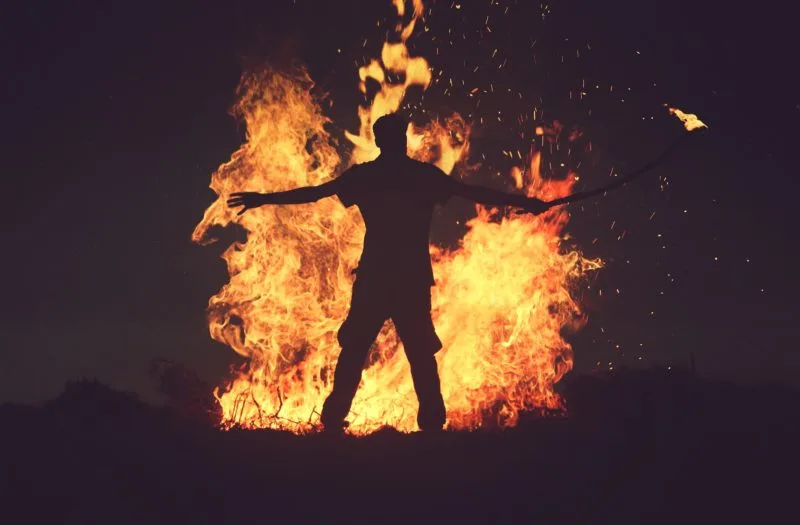 Roaring bonfire with silhouetted man standing arms outstretched